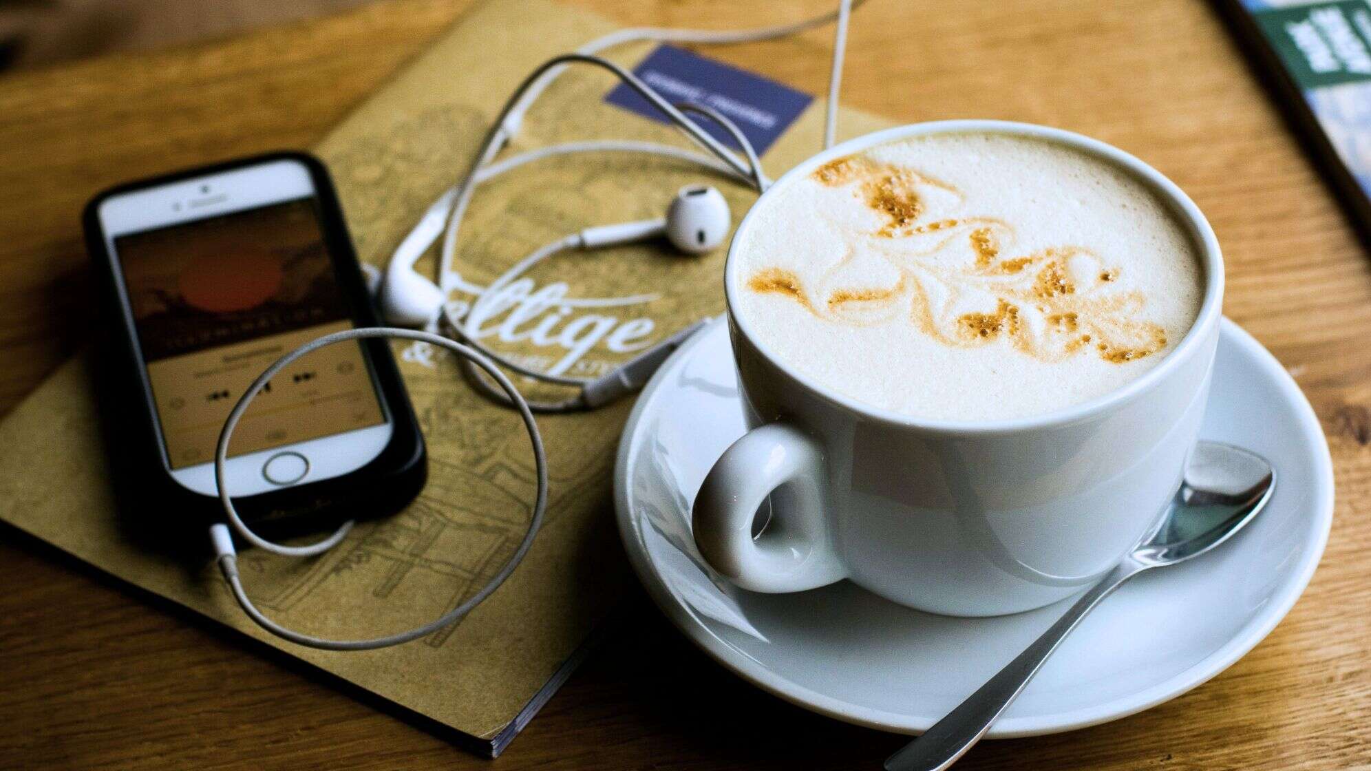 Kaffee neben einem Handy, auf dem Musik läuft