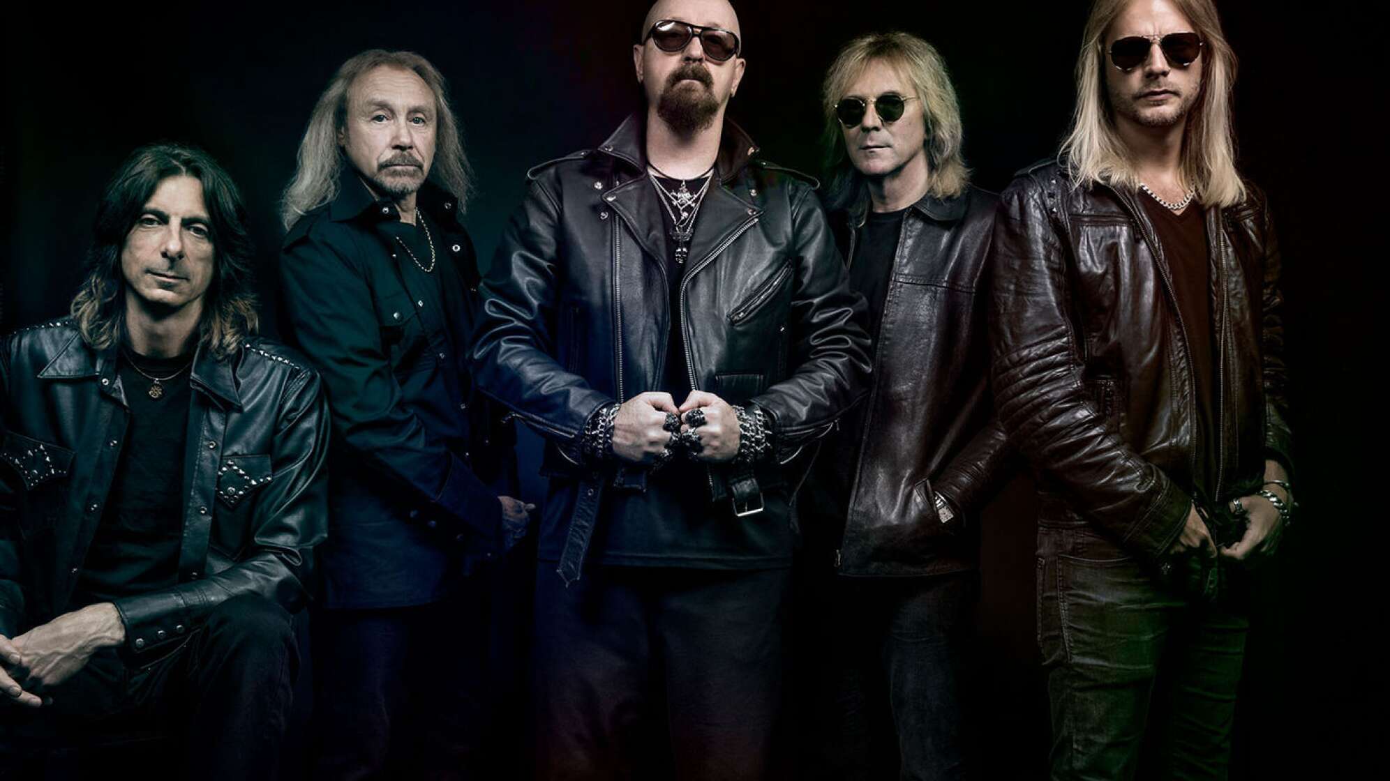 Judas Priest als Gruppenbild vor einem schwarzen Hintergrund