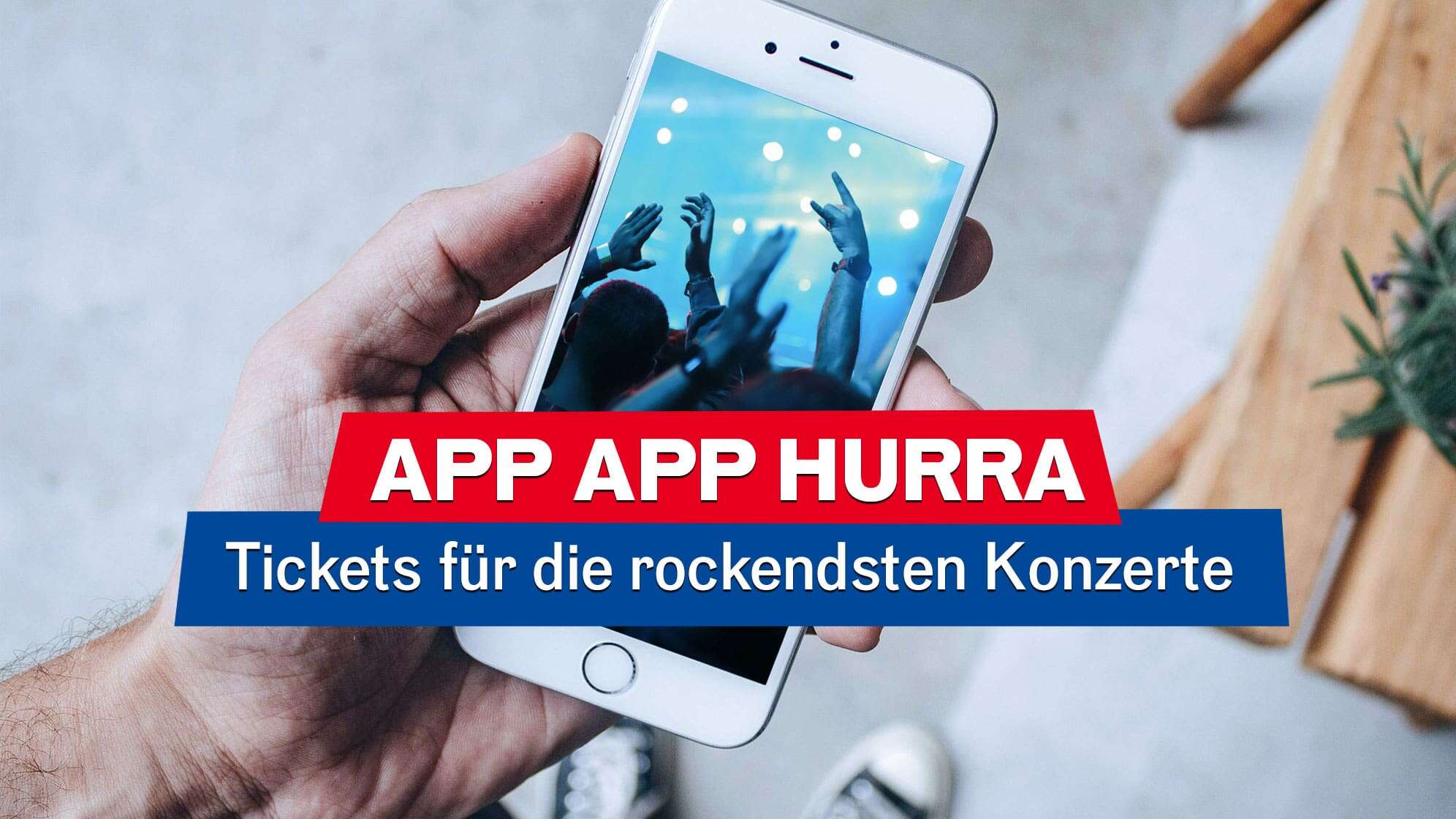 Ein Mann hält ein Smartphone in der Hand, auf dessen Bildschirm eine jubelnde Konzertmenge zu sehen ist - darüber liegt der Text: "App App Hurra - Tickets für die rockendsten Konzerte"